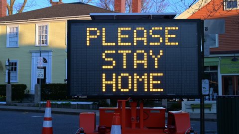 ROCKPORT, MASSACHUSETTS/USA - APRIL 22, 2020: A Large Sign Flashes Please Stay At Home, Lives Depend On It, Wear Your Mask, on the 50th Anniversary Celebration of Earth Day