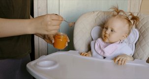 Caucasian mother feeding baby with spoon. RAW Graded footage 4K slow motion 60fps 