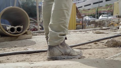 Man walking through working industrial site. Follow shot to a male worker feet in boots. engineering Legs of young man stepping on stones and cables Low angle view Close up Slow motion