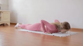 Young and Healthy woman in pink sportswear exercising at home practicing yoga poses in living room enjoying morning fitness workout on white carpet