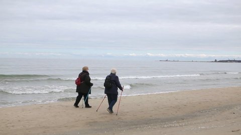 
Two elderly masked women are walking on the seashore during the Coronavirus epidemic. Spain. Malaga. 22. April. 2020. Coronavirus 2019-nCov.  Walk on fresh air during an epidemic.