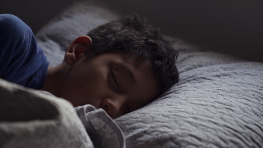 An Hispanic Kid Laying in Bed is Waking Up in the Morning After Sleeping All Night. Brown Skin Mixed Race 11 yrs Old Boy Opening His Eyes and Going Back To Sleep. Head over the pillow in bed napping. Royalty-Free Stock Footage #1050959530