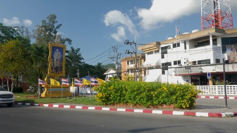 Koh Samui (Samui Island), Thailand - April 8, 2020: Portrait of King Vajiralongkorn, thai flags near road street with cars. Phrabat Somdet Phra Vajira Klao Chao Yu Hua King of Thailand since 2016