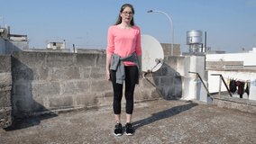 Young girl is doing lateral lunge inside on the roof of her home during quarantine of coronavirus. Female fitness training stay healthy. Concept self care at home and home workouts, quarantine sport