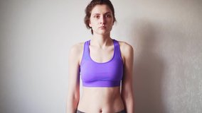 A beautiful woman in sportswear trains at home, in the bedroom. Caucasian girl watches online exercise, during self-isolation