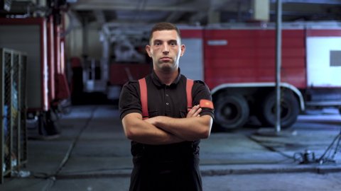 Firefighter portrait wearing uniform shirt and trousers. Fire truck parking in the background. 
