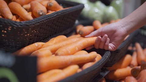 4k woman hand choosing carrots out of the basket shelf at super market grocery store shelf, fresh vegetable, lifestyle healthy eating, organic products, veggie food recipe menu, ingredient vitamin