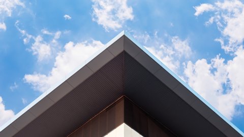 Abstract symmetry geometry triangular high building with timelapse clouds motion on blue sky in sunny day, Urban modern architecture creative design concept