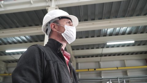 worker/engineer wearing disposal face mask for protect dust smoke and corona virus while working in workplace or factory.Camera turning around a worker.