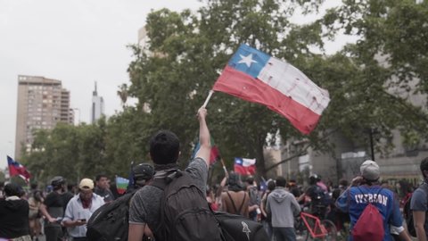 SANTIAGO, CHILE - October 28, 2019 Protesters walk raising the Chilean flag and head to Plaza Baquedano because of the current social crisis by the government of President Sebastian Piñera