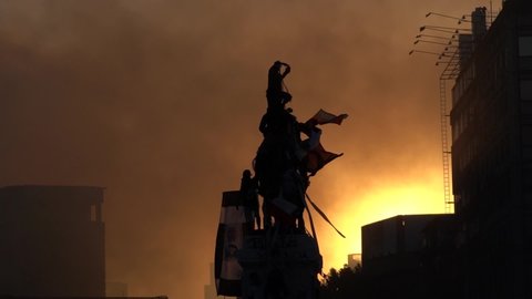 SANTIAGO, CHILE - October 24, 2019 Protestants raise their flags on statue of General Baquedano in Plaza Baquedano due to strong social crisis under sunset