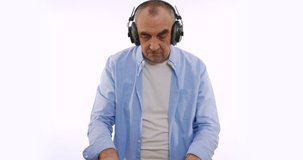 The old man in headphones, listening to music, dancing, smiling, cheerful. A very funky elderly grandpa dj.
