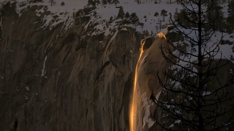 Pan shot of Firefall - seasonal Horsetail Falls illuminated by evening sunlight in Yosemite National Park, California