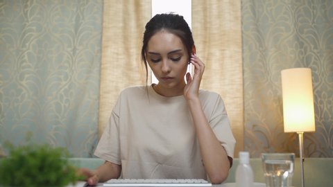 Young female manager makes a video conference, woman looks into the camera and talks, working at a computer, quarantine, work from home.