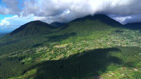 Aerial view Mountain peaks are covered tropical forest under clouds. Lake,mountain, clouds, blue sky, Bali, Indonesia. Mountain landscape. 4K video. Travel concept Aerial footage