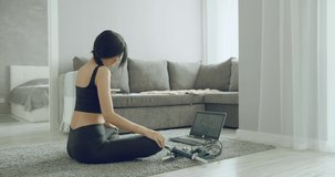 Sporty young woman doing stretching exercises online using a laptop at home. Healthy lifestyle concept. Sports during self-isolation