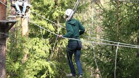 Caucasian Female in her 20s balancing on a rope bridge at a High Ropes Course or Adventure Park. Stock Video Clip Footage