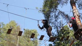 Caucasian male in his 20s balancing on a rope bridge at a High Ropes Course or Adventure Park. Stock Video Clip Footage