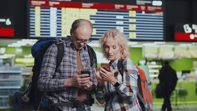 Senior man and woman travelers looking for flight information in smartphone at airport terminal. Mature couple travelers check-in by mobile phones - Powered by Shutterstock - Get 15% off with code: PIKWIZARD15