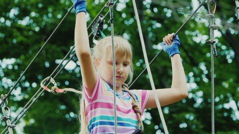 Portrait of a brave girl climbing ropes high in tree branches