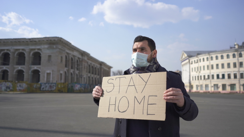 World pandemic team. Man in medical mask stand with poster  on city  street. 


