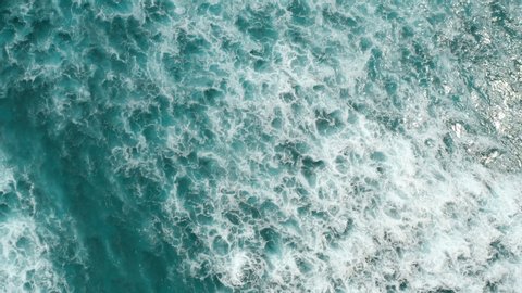 Timelapse. Aerial top view waves break on reef in a blue ocean. Sea waves on beautiful beach aerial view drone 4k shot. Bird's eye view of ocean waves crashing against an empty stone from above.