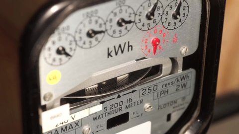 Close-up of a domestic electric meter and dial turning. Concept for energy, utility bills, price increase, meter reading and electricity usage monitoring.