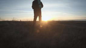 Silhouette of a man with a backpack against bright sky sunset. Sun goes down. Travel Concept. Slow video tourist go travel nature outdoors lifestyle.