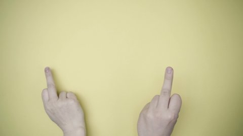 Two hands show gestures: fuck you! Yellow background.