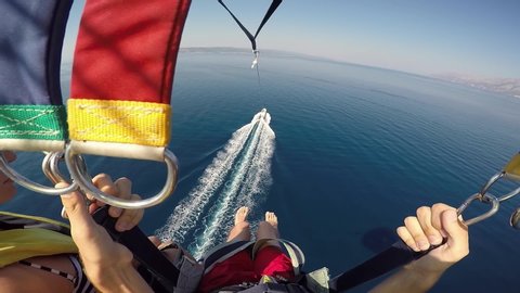 Parasailing over Adriatic sea young couple legs above crystal blue water point of view action camera. Soaring high above water