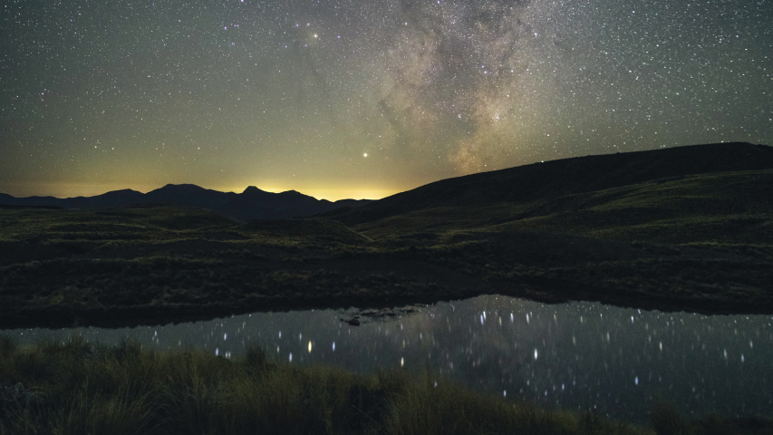Time lapse of the Milky Way rising, followed by the moon, over a still lake in the Kahurangi National Park, NZ	