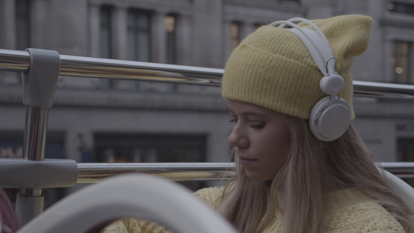 Handheld Medium Shot Of Teenage Girl Wearing Headphones And Yellow Hat On Open Top London Bus | Shutterstock HD Video #1051052152