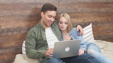Young couple watches positive video on laptop lying at home quarantine.