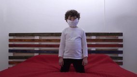 Europe, Italy , Milan -  children boy  five years with mask at home during quarantine at home due n-cov19 Coronavirus outbreak - life style in apartment - dancing with music in a bed room 