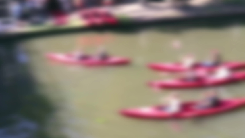 Abstract blurred people in canoes paddling down a canal for fun sporting activity in sunshine