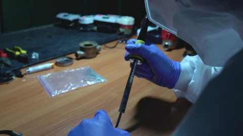 Lab technician soldering secret experimental device in clandestine laboratory