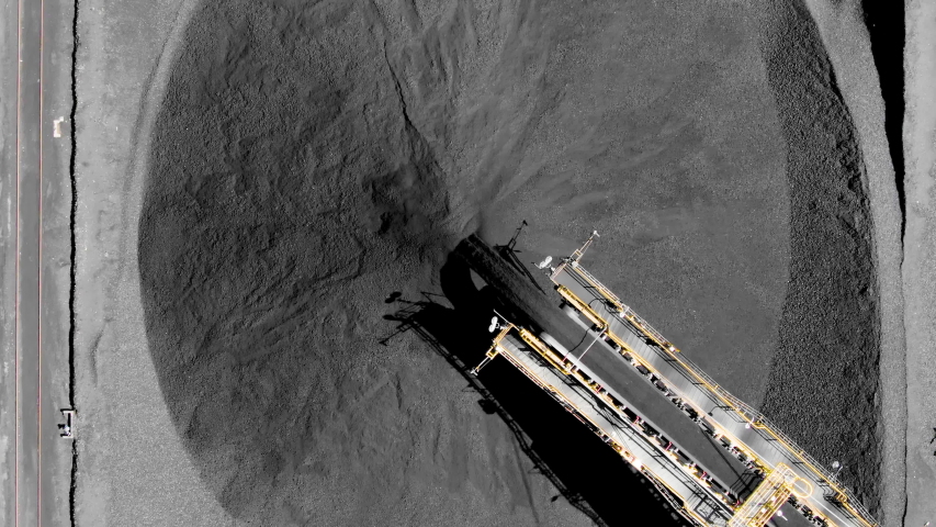 Aerial top down of coal conveyor belt piling up coal at a depot for export/import. Fossil fuel reliance, sustainability and global warming concepts. Royalty-Free Stock Footage #1051071811