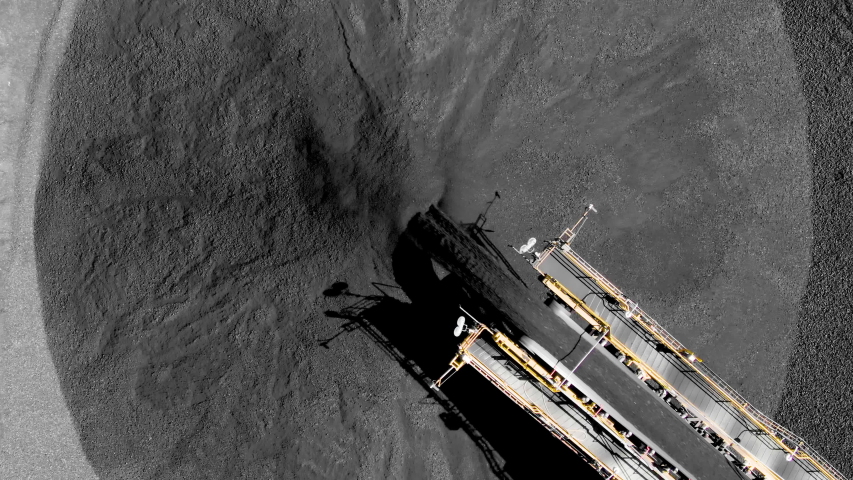 Aerial top down of coal conveyor belt piling up coal at a depot for export/import. Fossil fuel reliance, sustainability and global warming concepts.