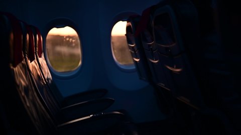 Inside interior of an empty airplane. Plane taking off with no people or passengers on the empty seats. Nobody flying on the airplane. Groud moving seen through the window