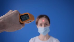 Slow motion: man hand holding yellow pyrometer to measure temperature of woman in medical face mask - close up view, selective focus. Healthcare, measurement, disease, infection, coronavirus concept - Powered by Shutterstock - Get 15% off with code: PIKWIZARD15