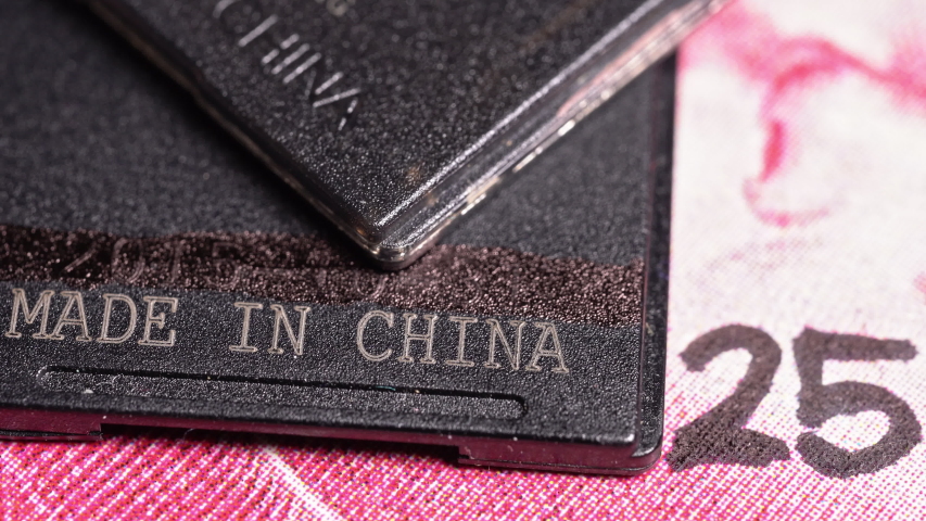 Made in china text written on a piece of plastic over a yuan bill with the number 25 on it. Concept of Made in China 2025, a blueprint to upgrade the manufacturing capabilities of Chinese industries Royalty-Free Stock Footage #1051087954