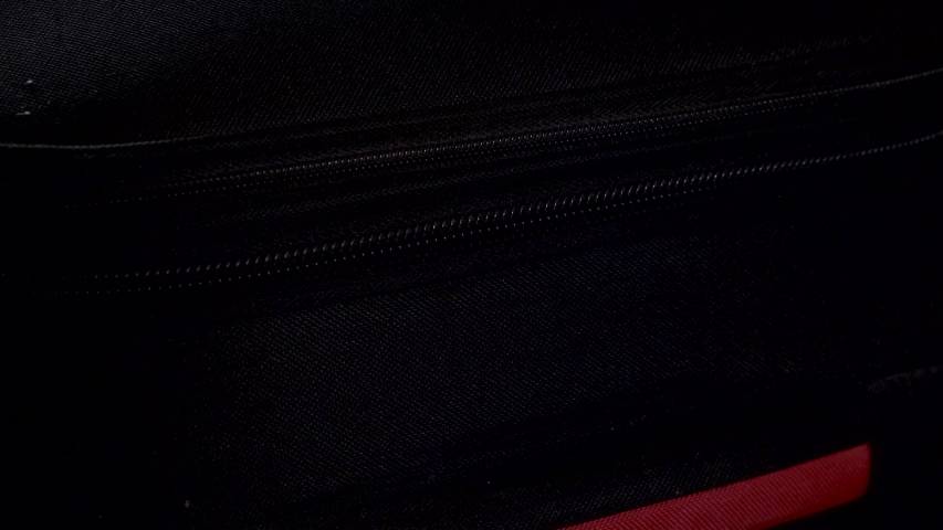 Close-up of opening zipper on suitcase.