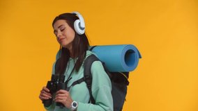 Tourist in headphones dancing and smiling at camera isolated on yellow