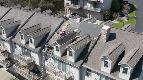 Morgantown, WV - 22 April 2020: Aerial view of roofing contractors replacing the old roof tiles on a townhouse roof in Morgantown