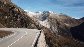 Professional road cyclist ride on carbon bicycle up curve on narrow swiss mountain road. Legendary Furka pass in distance. Cycling inspiration and epic destination for athletic goals