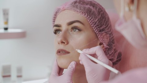 cosmetologist marks the face before the Botox injection procedure