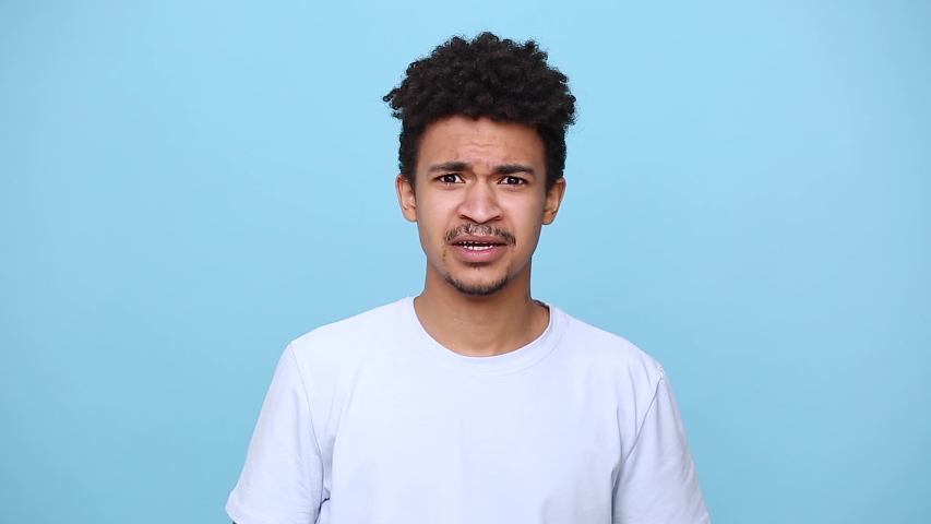 Angry mad african american young guy 20s in white t-shirt isolated on blue background studio portrait. People sincere emotions lifestyle concept. Look at camera screaming scolding protest waving hands Royalty-Free Stock Footage #1051104526