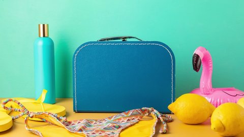 Stop motion animation of beach accessories getting in blue suitcase. Holiday planning, summer vacations concept