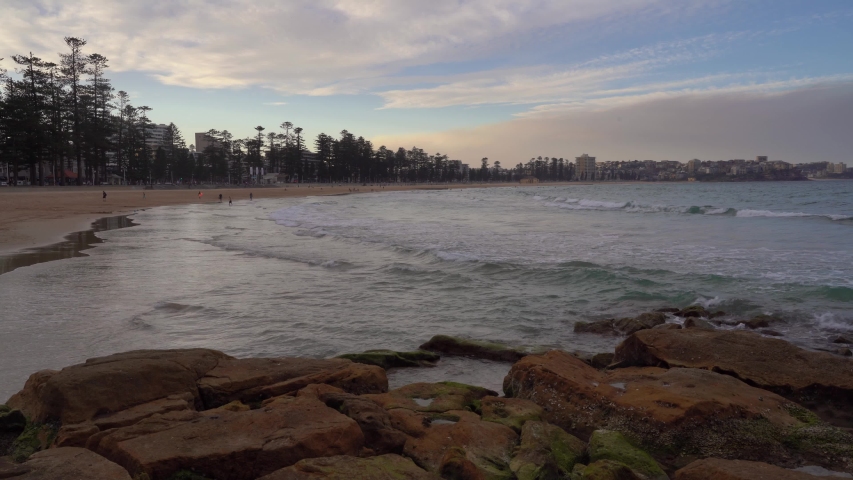 Sydney, Australia - People Walking In The Lush Shore Of The Sea With Waves Calmly Splashing On The Rocks During Sunset - Wide Shot
