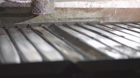 Slow motion shot of pouring melted white metal from a casting ladle into the metal mold.